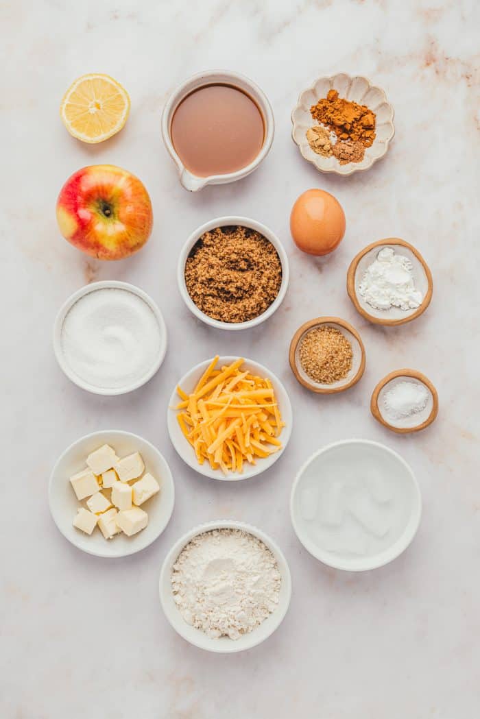 Various white bowls with the ingredients for caramel apple pie with cheddar. 