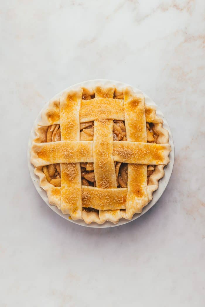 An unbaked apple pie with an egg wash and sugar sprinkled on it. 