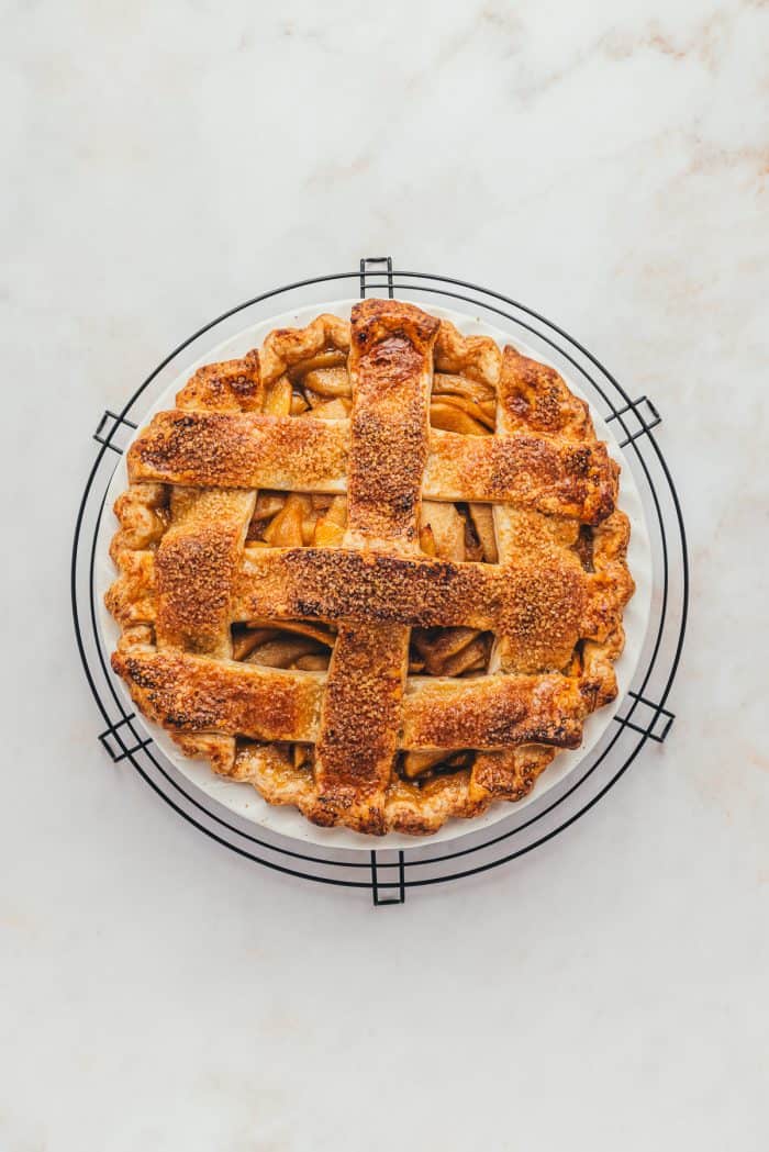 A baked apple pie with a lattice crust on a cooling rake.