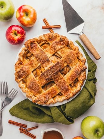 An apple cheddar pie in the pie dish with a green napkin.