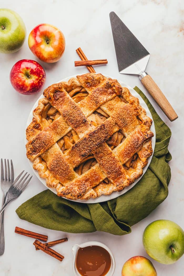 An apple cheddar pie in the pie dish with a green napkin. 