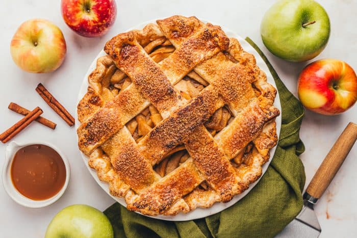 An apple cheddar pie in the pie dish with a green napkin.