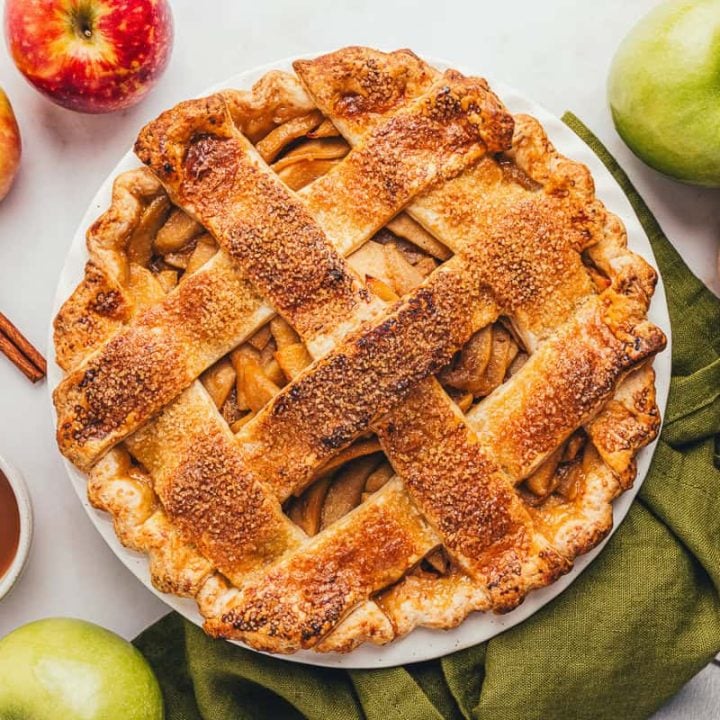 An apple cheddar pie in the pie dish with a green napkin.