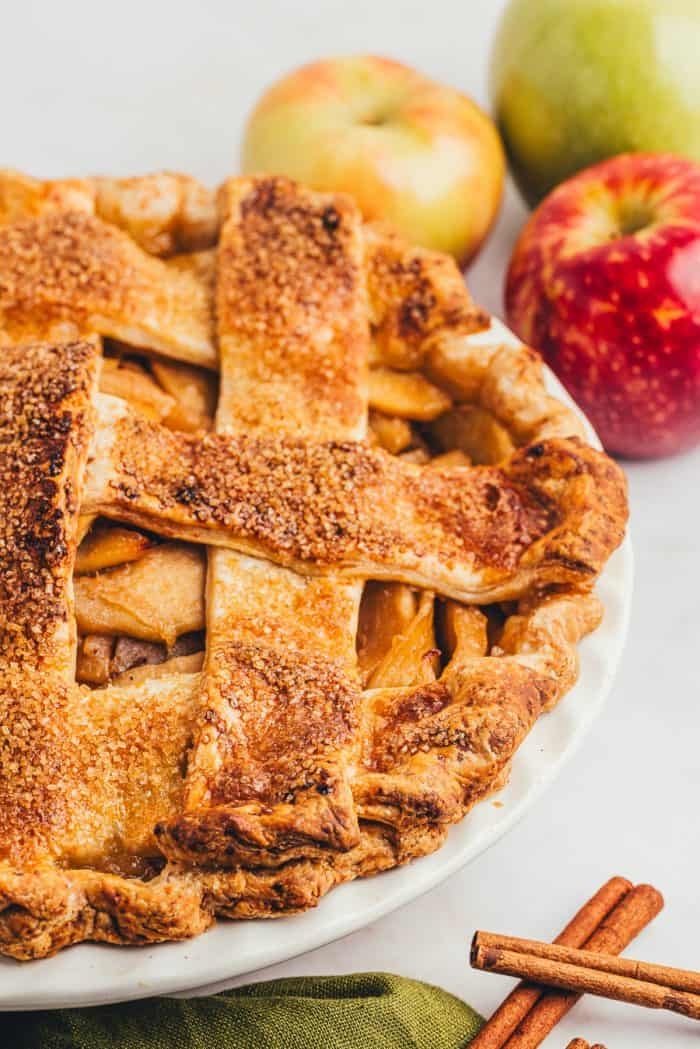 A side view of a caramel apple pie in a white pie dish.