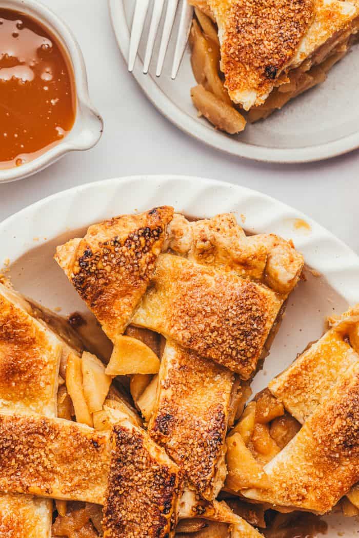 A white pie dish with three slices of apple pie in it.