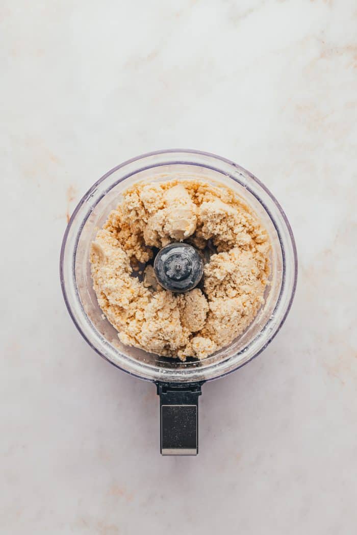 A food processor with flour, sugar, salt. cheddar cheese, and butter.