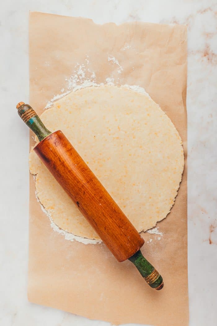 Pie dough that has been rolled out into a circle with a wooden rolling pin. 