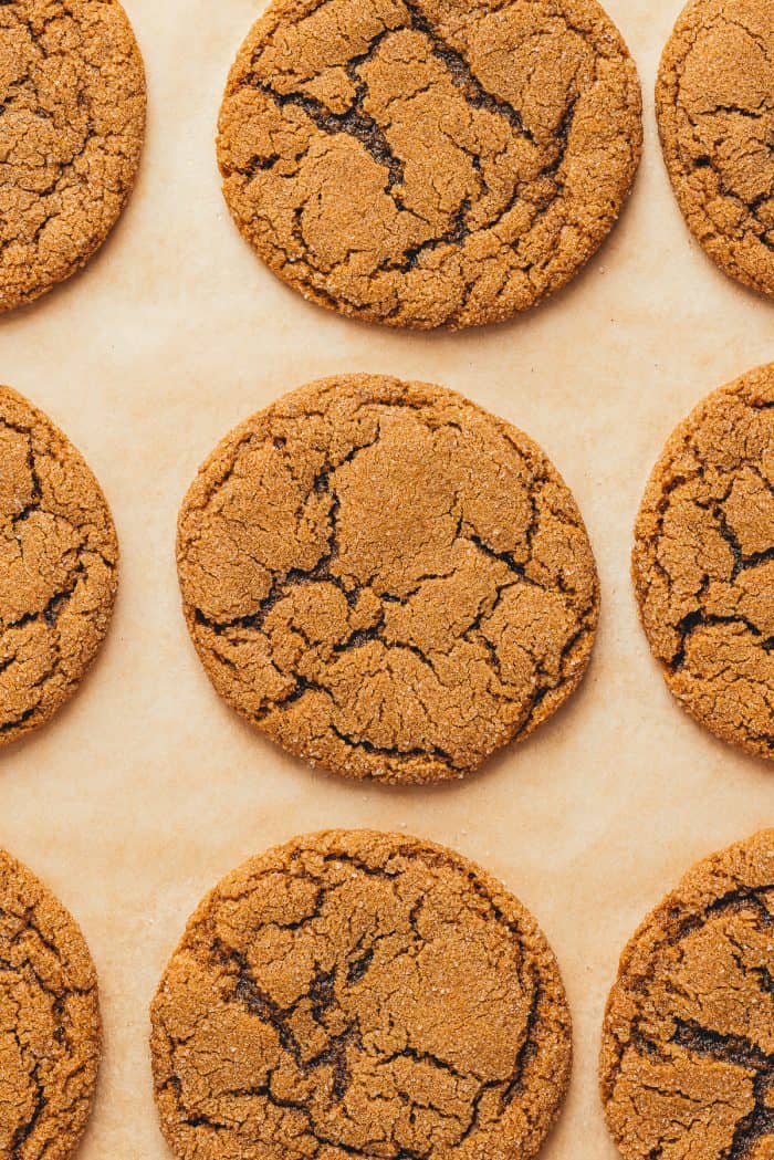 A baking tray with parchment paper and baked double ginger molasses cookies.