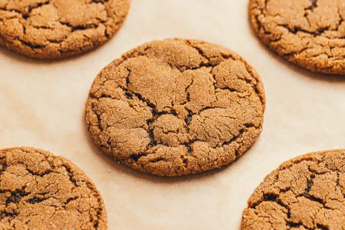 A baking tray with parchment paper and baked double ginger molasses cookies.