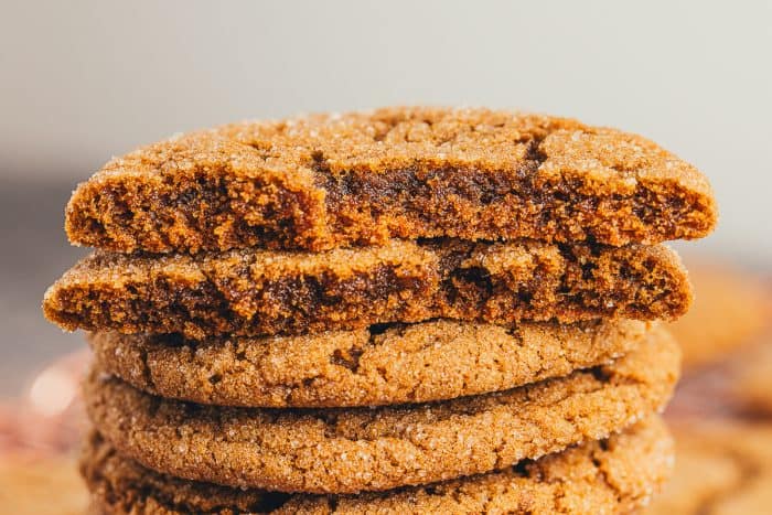 A pile of ginger molasses cookies with a cookie broken in half.