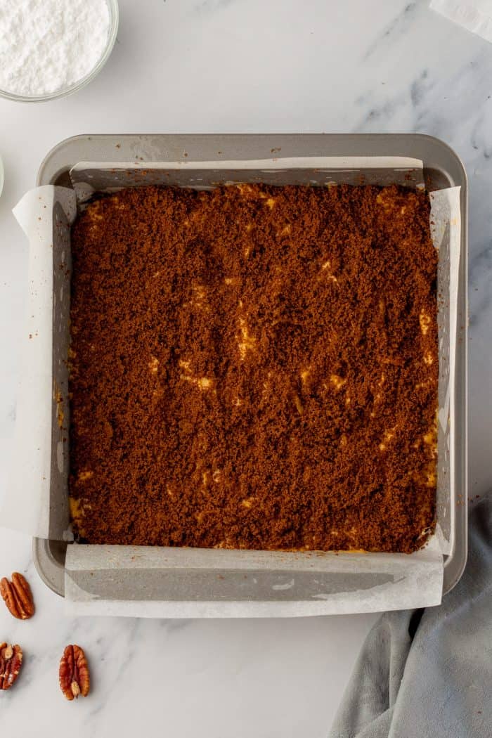 The pumpkin cake batter with a layer of cinnamon sugar in a cake pan with parchment paper.