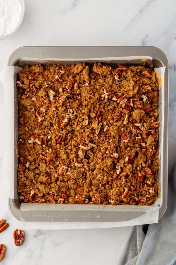 Unbaked pumpkin cake with a pecan streusel topping in a cake pan.