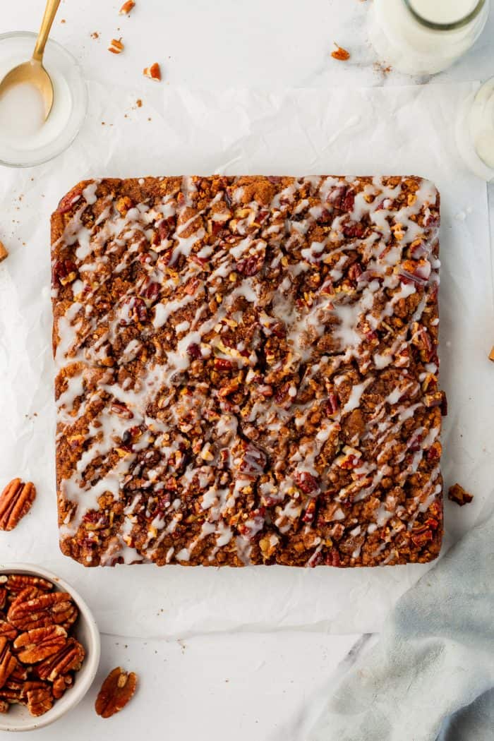 Baked pumpkin pecan coffee cake that has been removed from the cake pan with icing drizzled all over it.