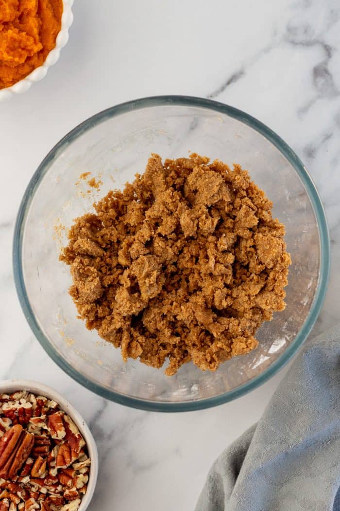 Brown sugar, cinnamon, butter, and flour, mixed together in a glass bowl.