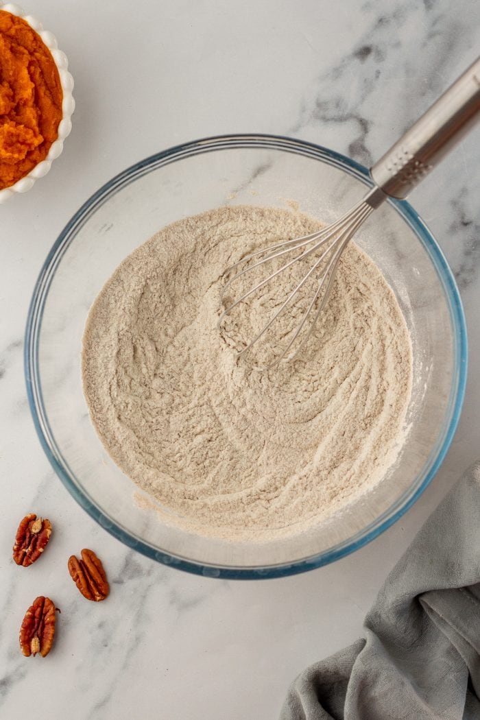 A glass bowl filled with flour, cinnamon, baking soda, and baking powder that has been mixed together.