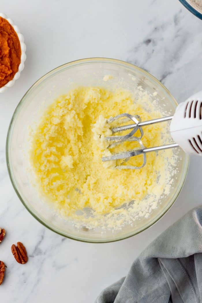 A glass bowl that is filled with butter and sugar that has been mixed.