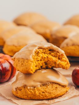 Two pumpkin spice cookies stacked on each other and one has a bite taken out of it.