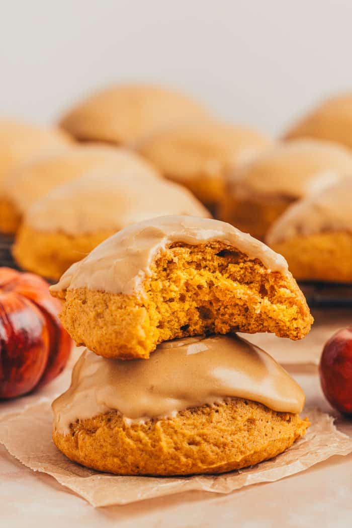 Two pumpkin spice cookies stacked on each other and one has a bite taken out of it.