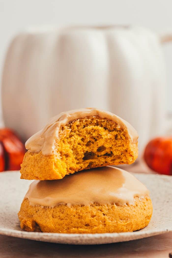 Two pumpkin spice cookies stacked on each other and one has a bite taken out of it.