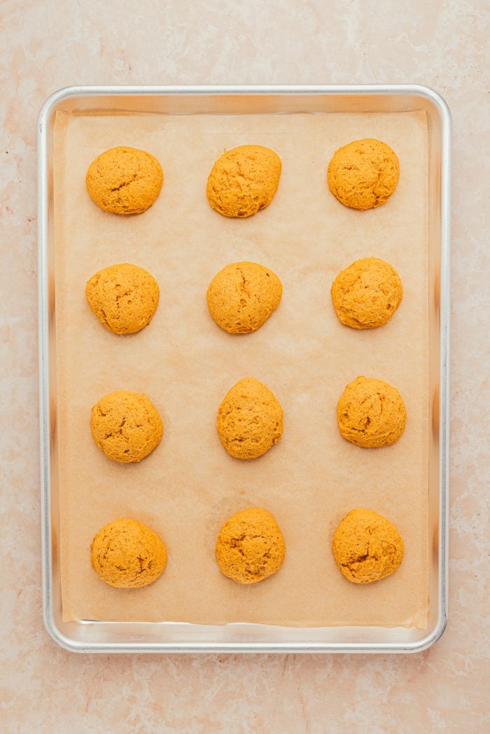 A baking sheet with parchment paper and baked pumpkin pie cookies.