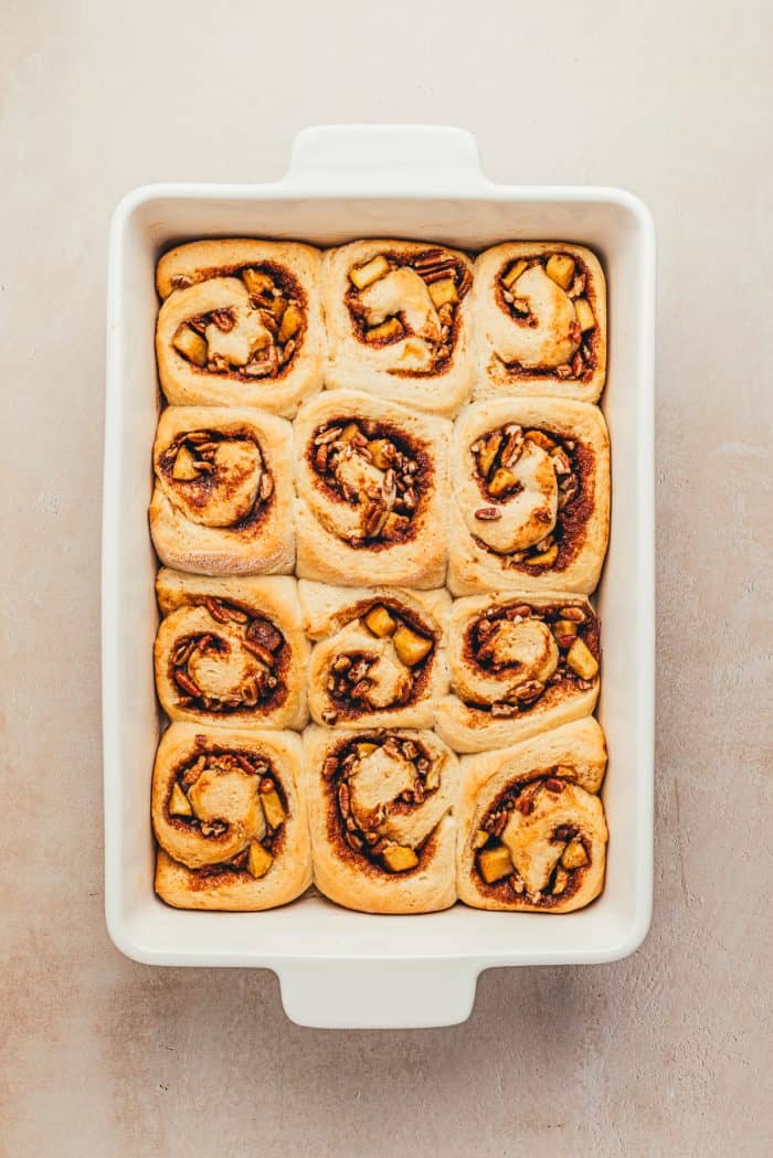 A white baking dish with baked cinnamon rolls.