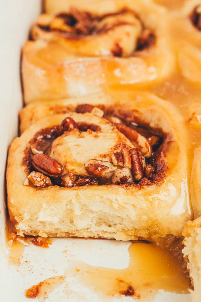 A closeup of caramel apple cinnamon rolls in a white baking dish.