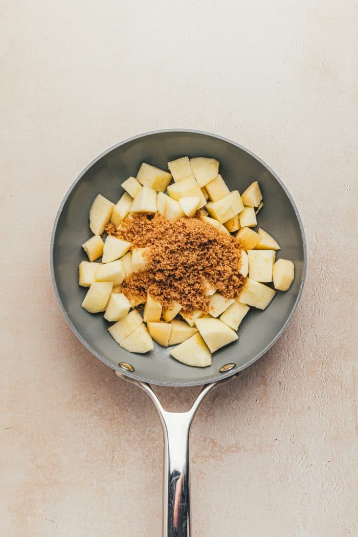 Chopped apples with brown sugar in a skillet.