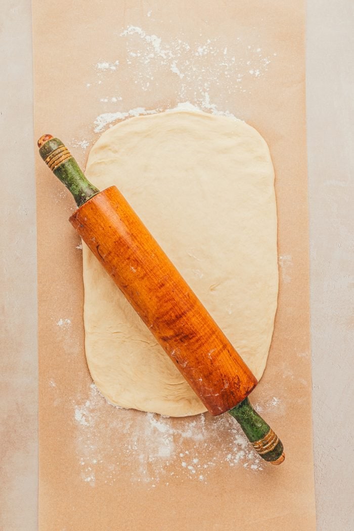 The dough is rolled out with a wooden rolling pin.