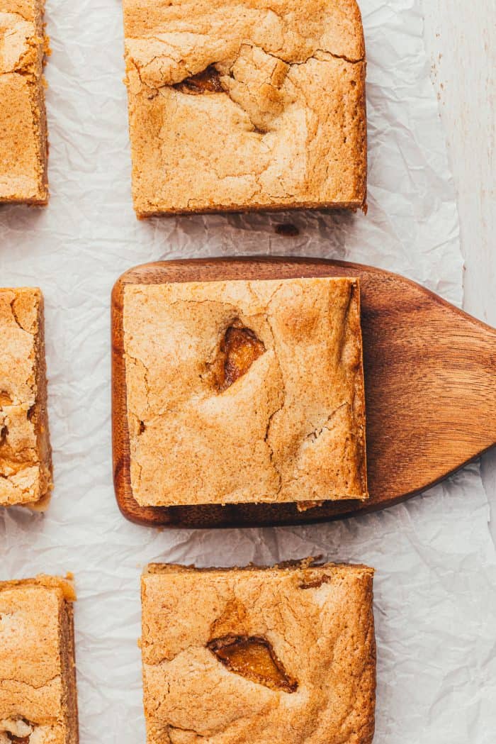 Six Apple Blondies and one is being lifted by a wooden spatula.