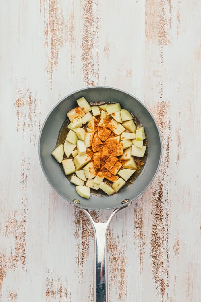 Cubed green apples in a saute pan with cinnamon.