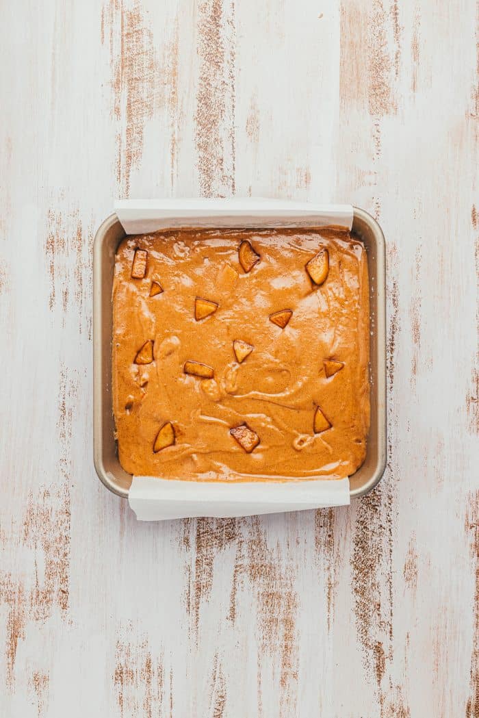 A square baking pan with raw apple Blondie batter.