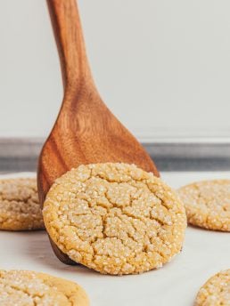 A wooden spatula that is lifting a browned butter sugar cookie.