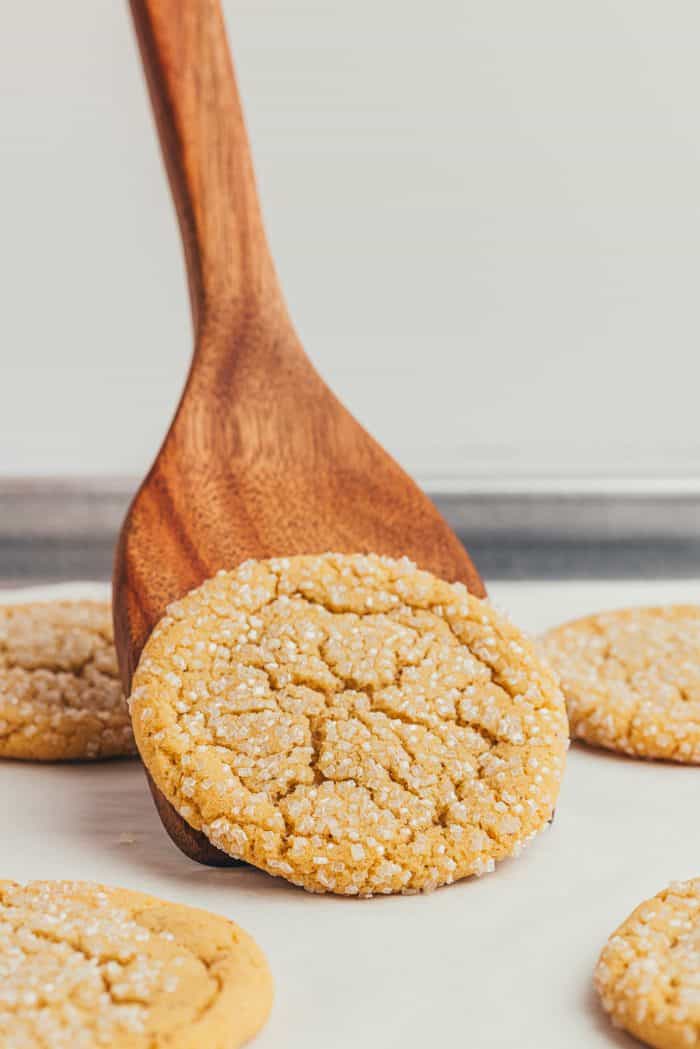 A wooden spatula that is lifting a browned butter sugar cookie.