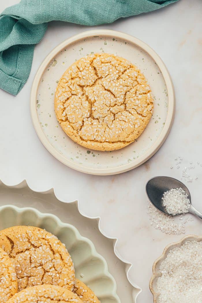 A white plate with a brown butter cookie with a bite taken out of it.