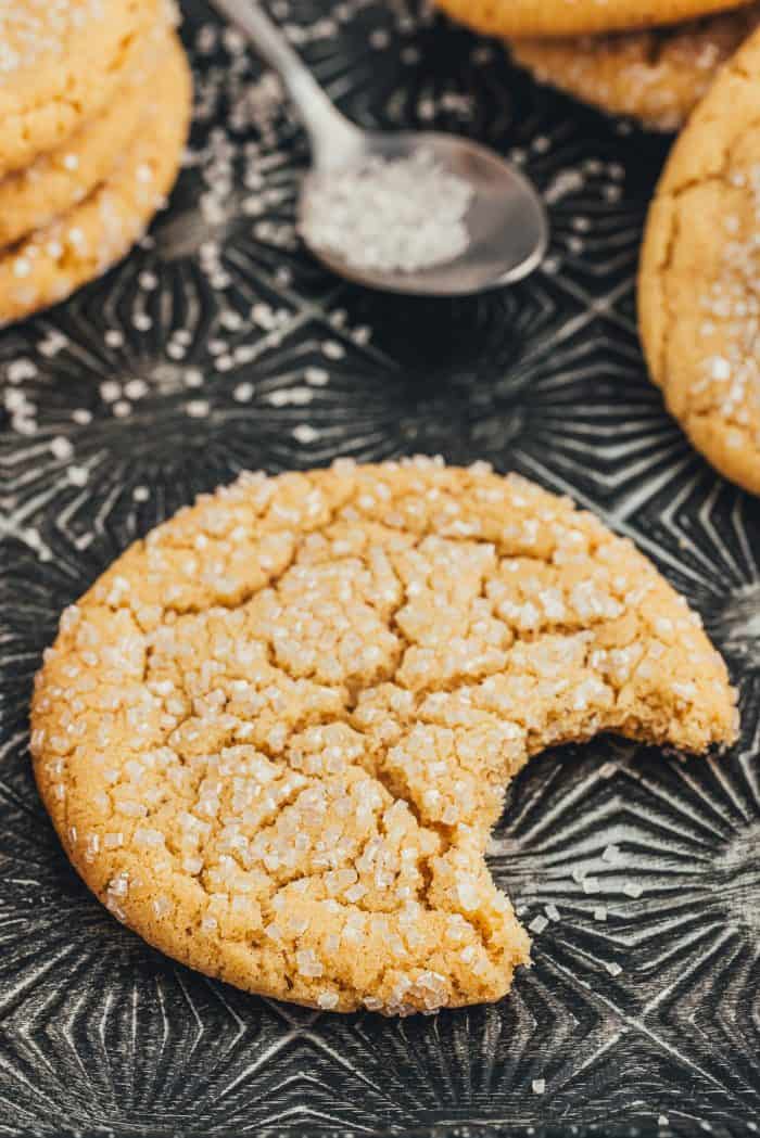 Various brown butter sugar cookies on a vintage cookie tray and one cookie has a bite taken out of it.