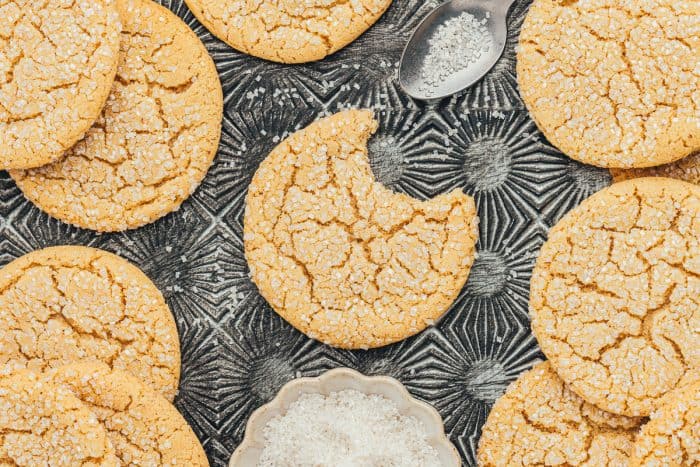 Various brown butter sugar cookies on a vintage cookie tray and one cookie has a bite taken out of it.