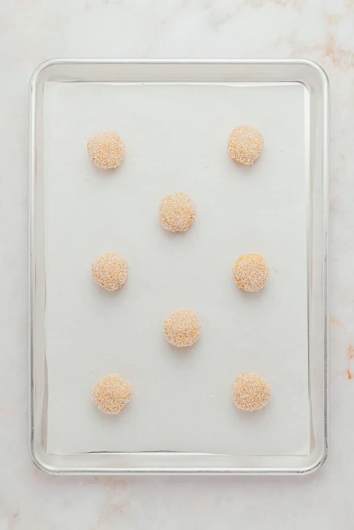 A cookie tray with various balls of raw sugar cookie dough,