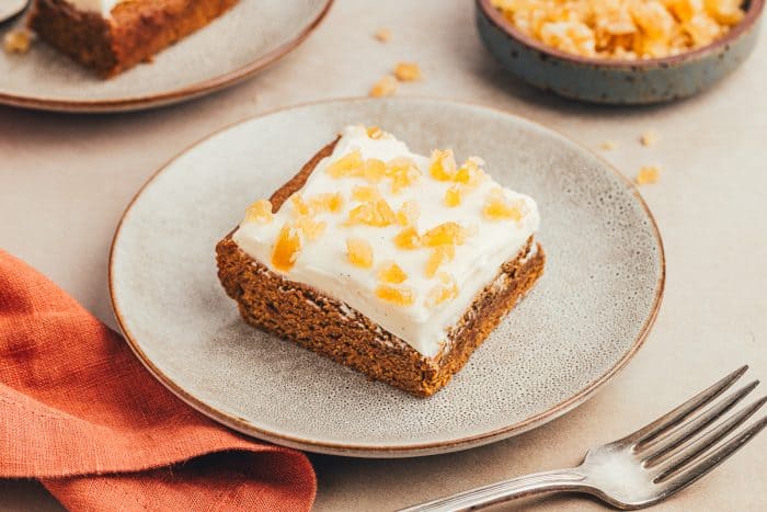 A gray plate with a gingerbread cookie bar on it with a fork nearby.