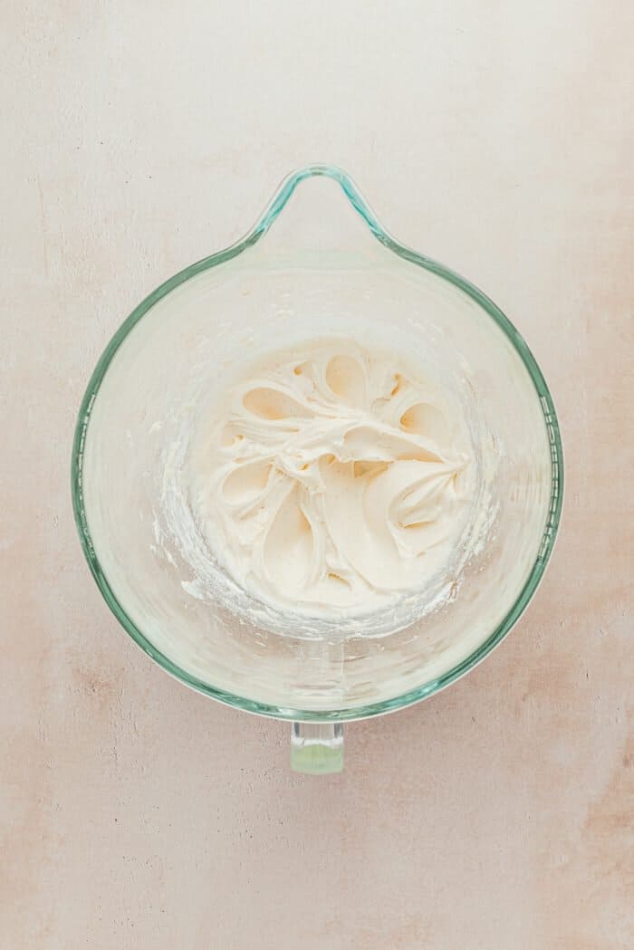 A glass mixing bowl with frosting.