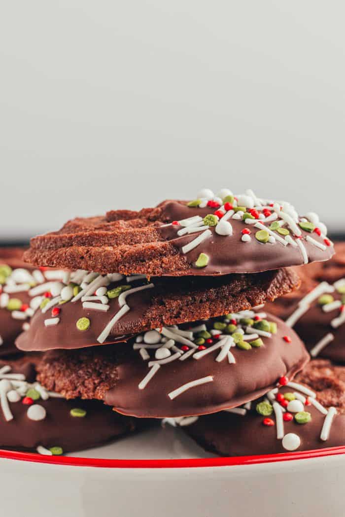 A pile of cookies on a white plate with a red rim.