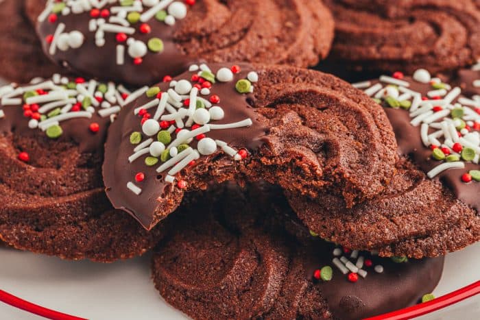 An up close photo of a bite taken of a chocolate orange cookie on a pile of cookies.