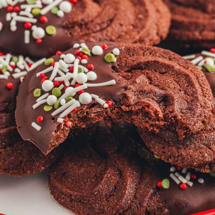 An up close photo of a bite taken of a chocolate orange cookie on a pile of cookies.