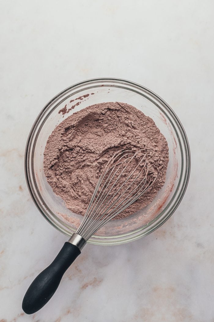 A glass bowl with the dry ingredients and a whisk.