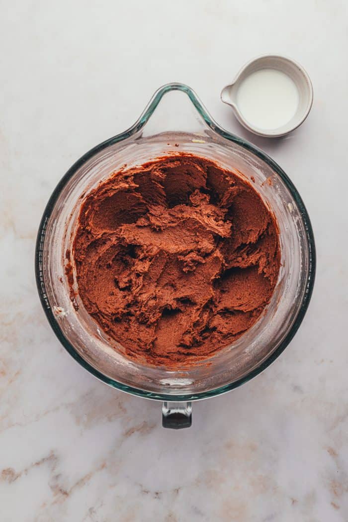 A glass bowl with the cookie dough mixed with a little bit of milk.