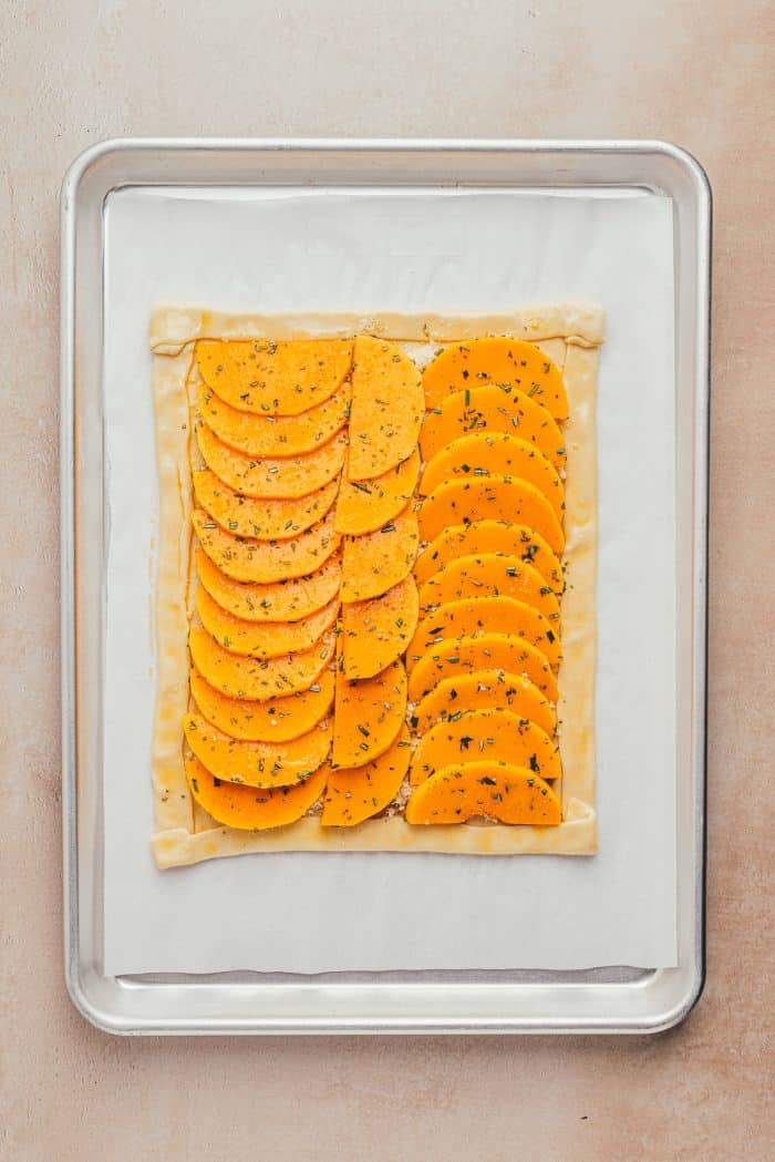 An unbaked butternut squash on a baking sheet.