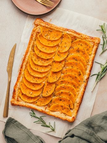 An image of butternut squash tart with a golden knife nearby.