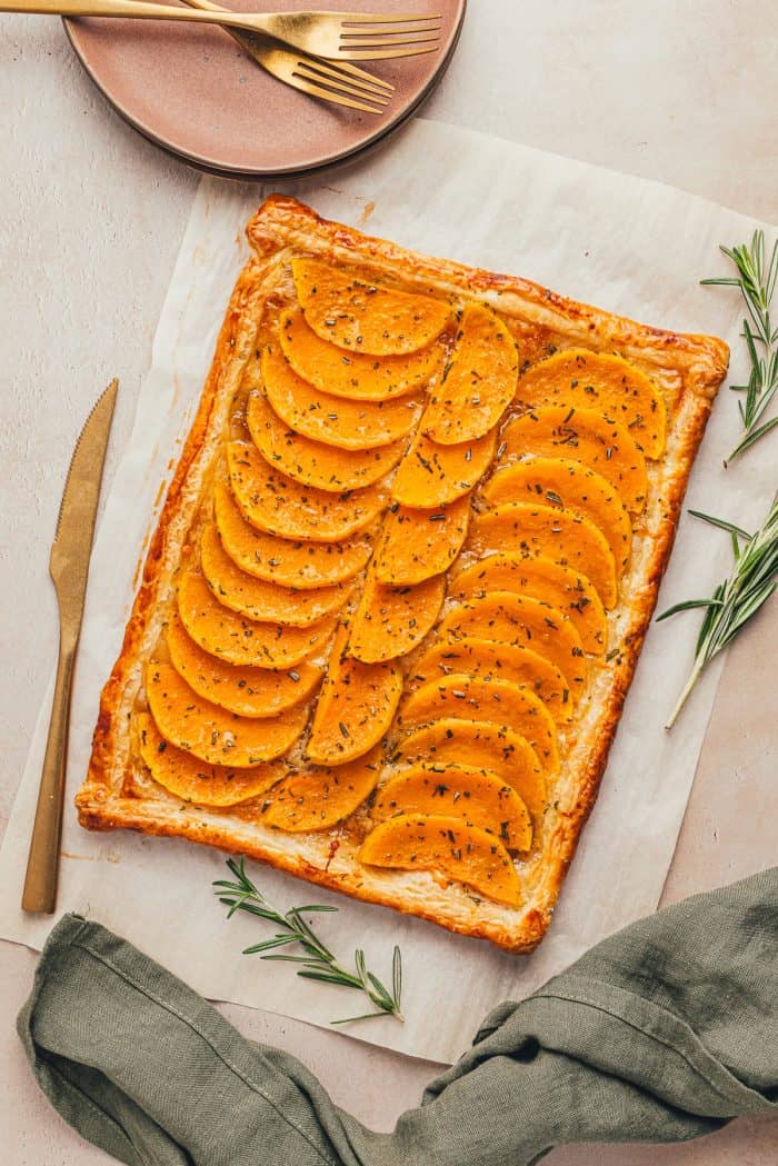 An image of butternut squash tart with a golden knife nearby.