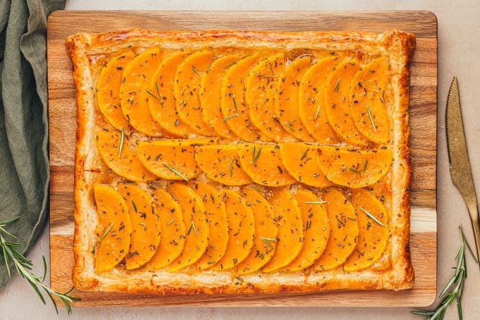 An image of the whole easy butternut squash tart on a wooden cutting board.