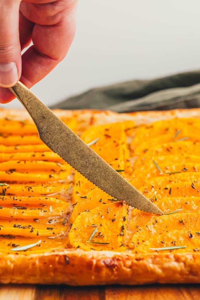 A knife cutting through a butternut tart.