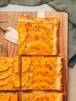 Slices of butternut squash on a wooden cutting board.